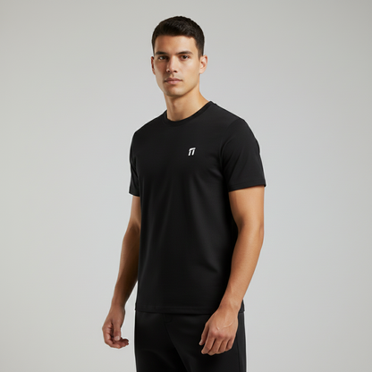 Man wearing a black t-shirt with a small logo on a gray background