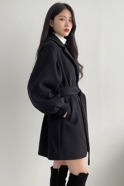 Female model wearing black belted coat - side profile
