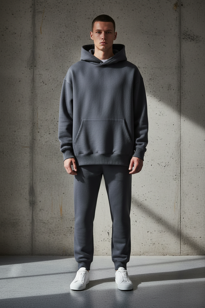 Oversized heavyweight charcoal hoodie front view on model against concrete wall