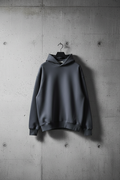 Oversized heavyweight charcoal hoodie hanging on concrete wall